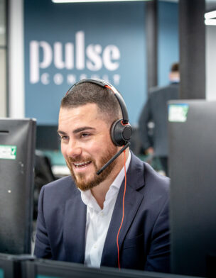 A man wearing a headset sat at his desk on a video call.